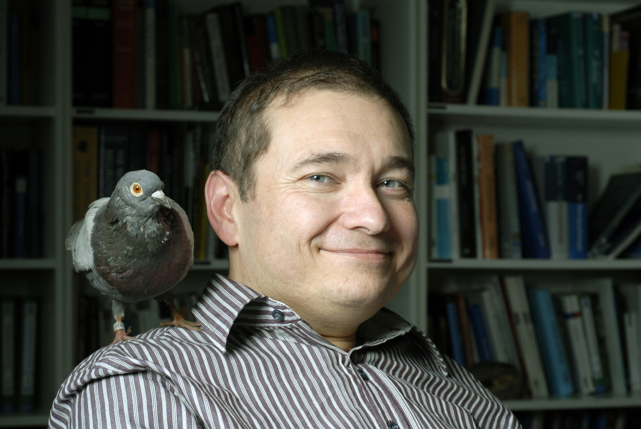 Foto do Prof. Dr. Onur Güntürkün com uma pomba pousada no ombro