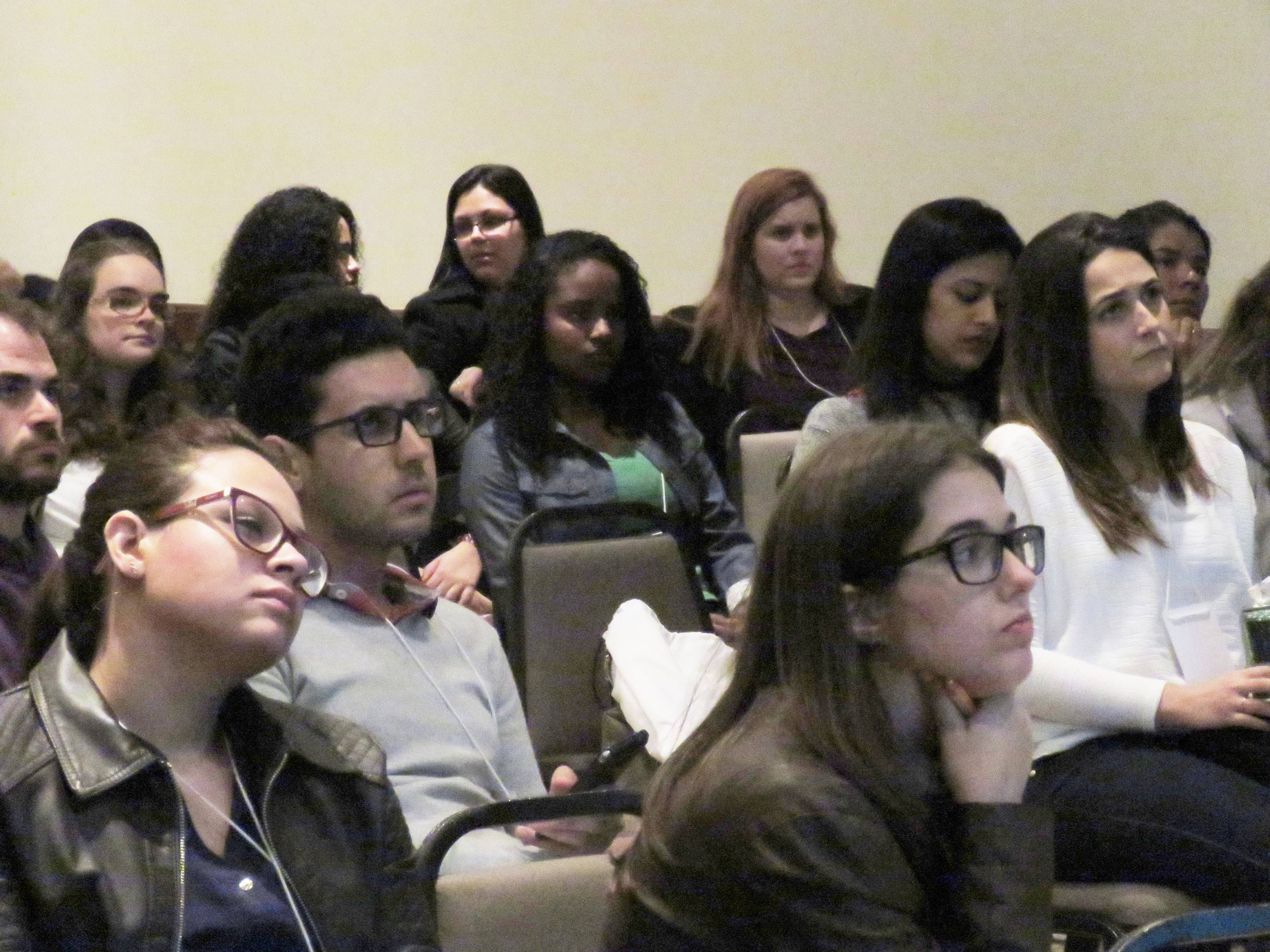 A imagem mostra diversos participantes sentados olhando na mesma direção enquanto ouvem uma palestra do Research in Germany
