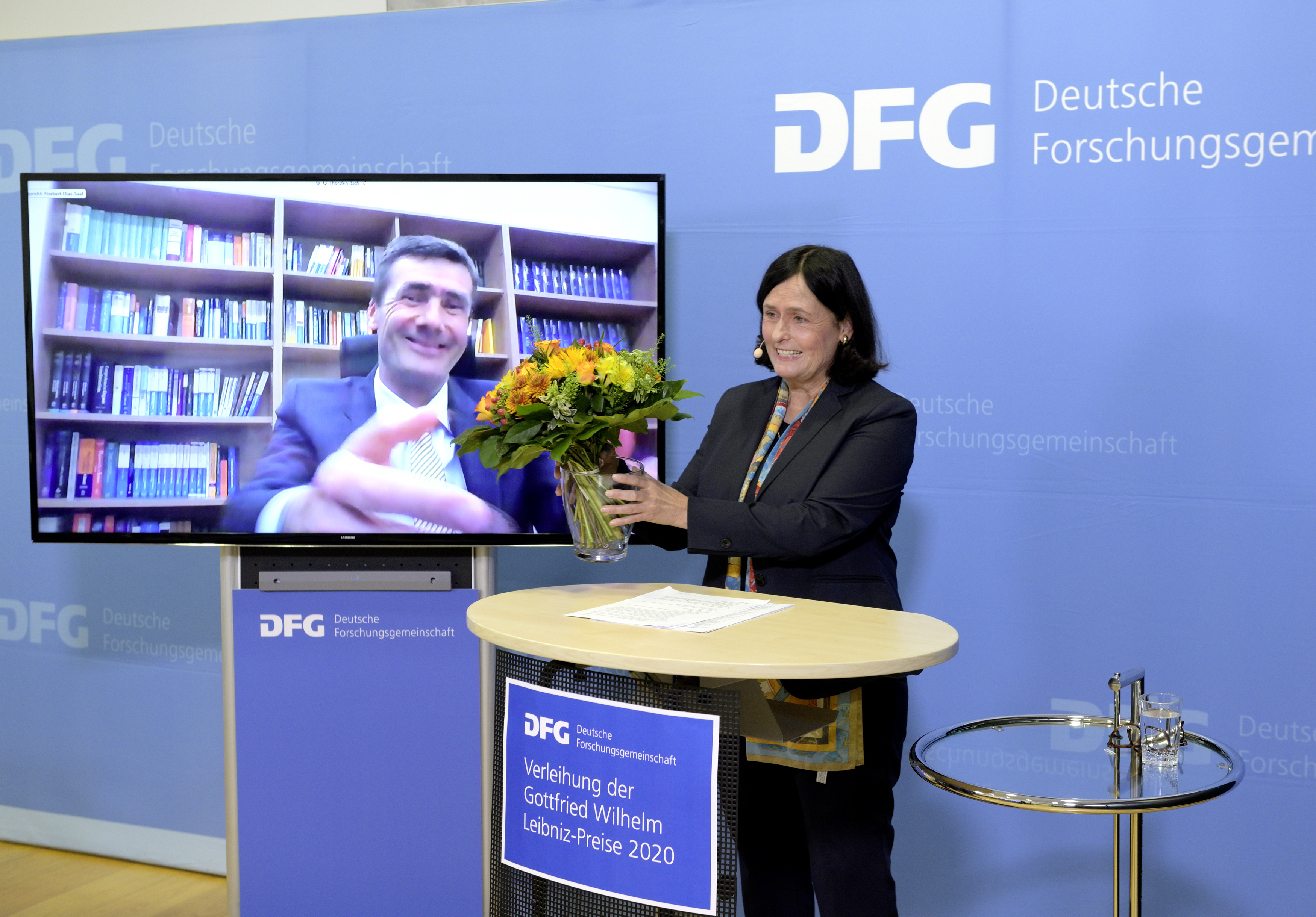 DFG-Präsidentin Katja Becker gratuliert Thorsten Bach von Pult zu Bildschirm