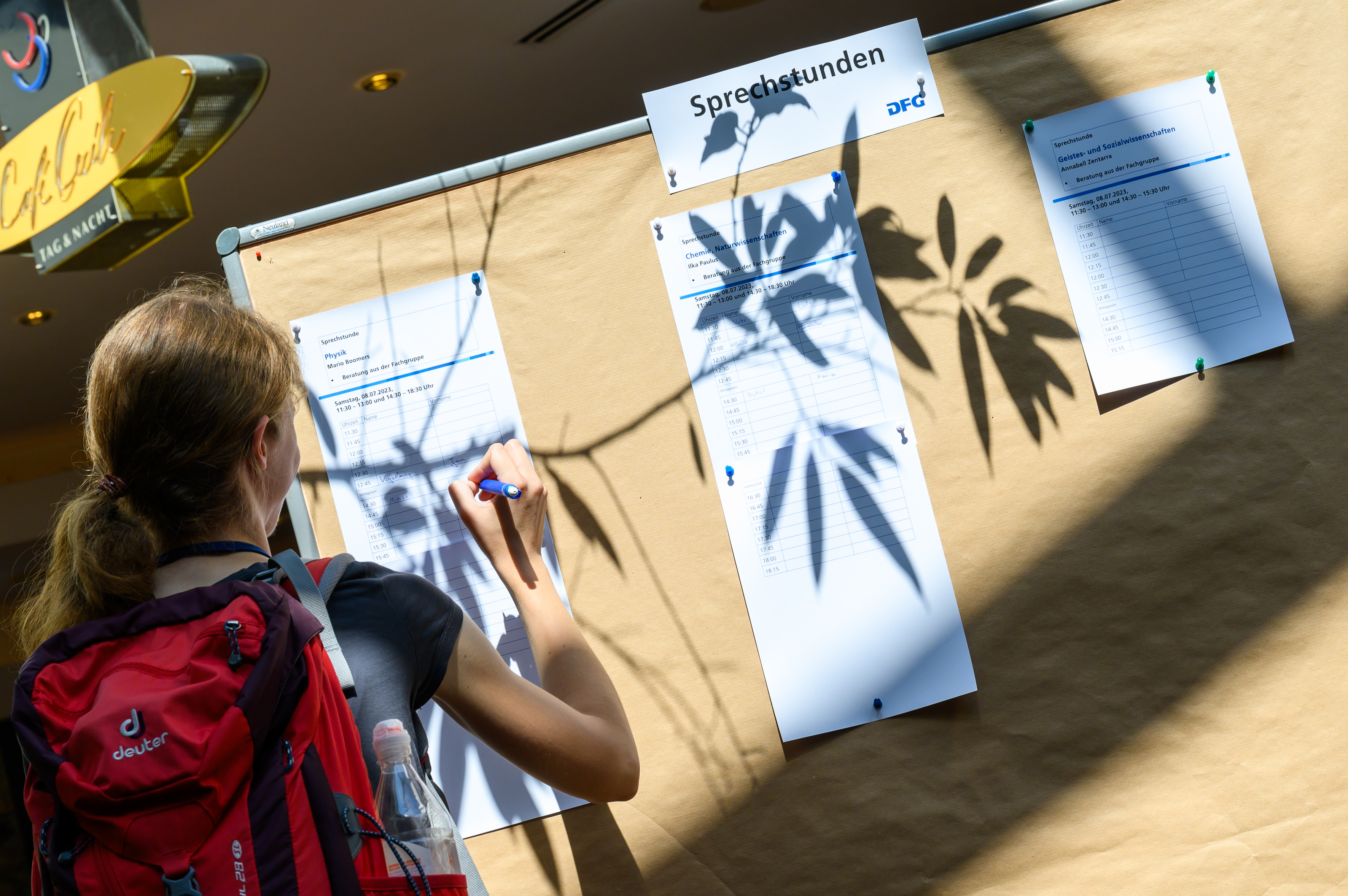 Eine Frau schreibt sich für eine Sprechstunde an einem Flipchart ein