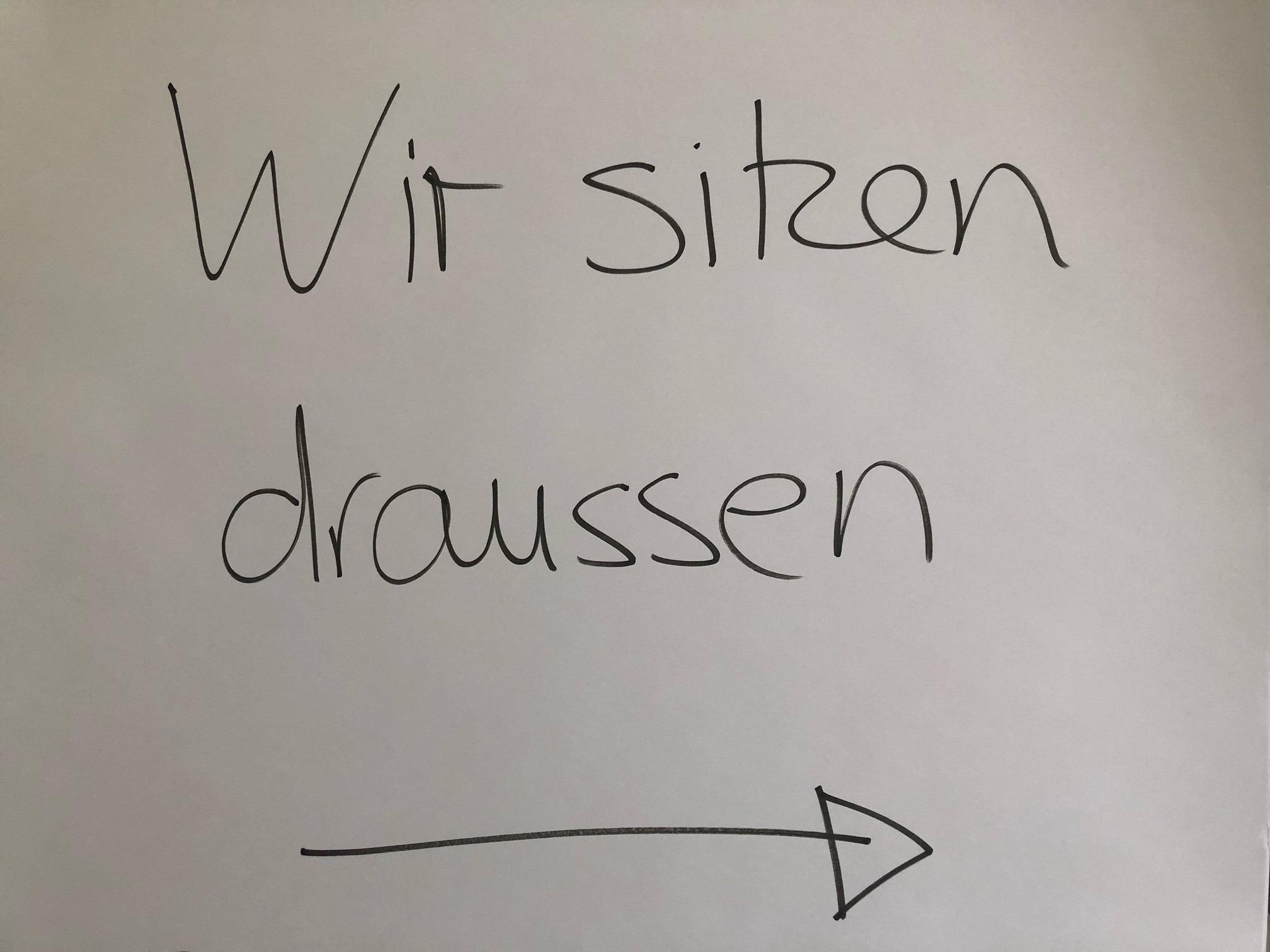 Handgemaltes Schild "Wir sitzen draußen"