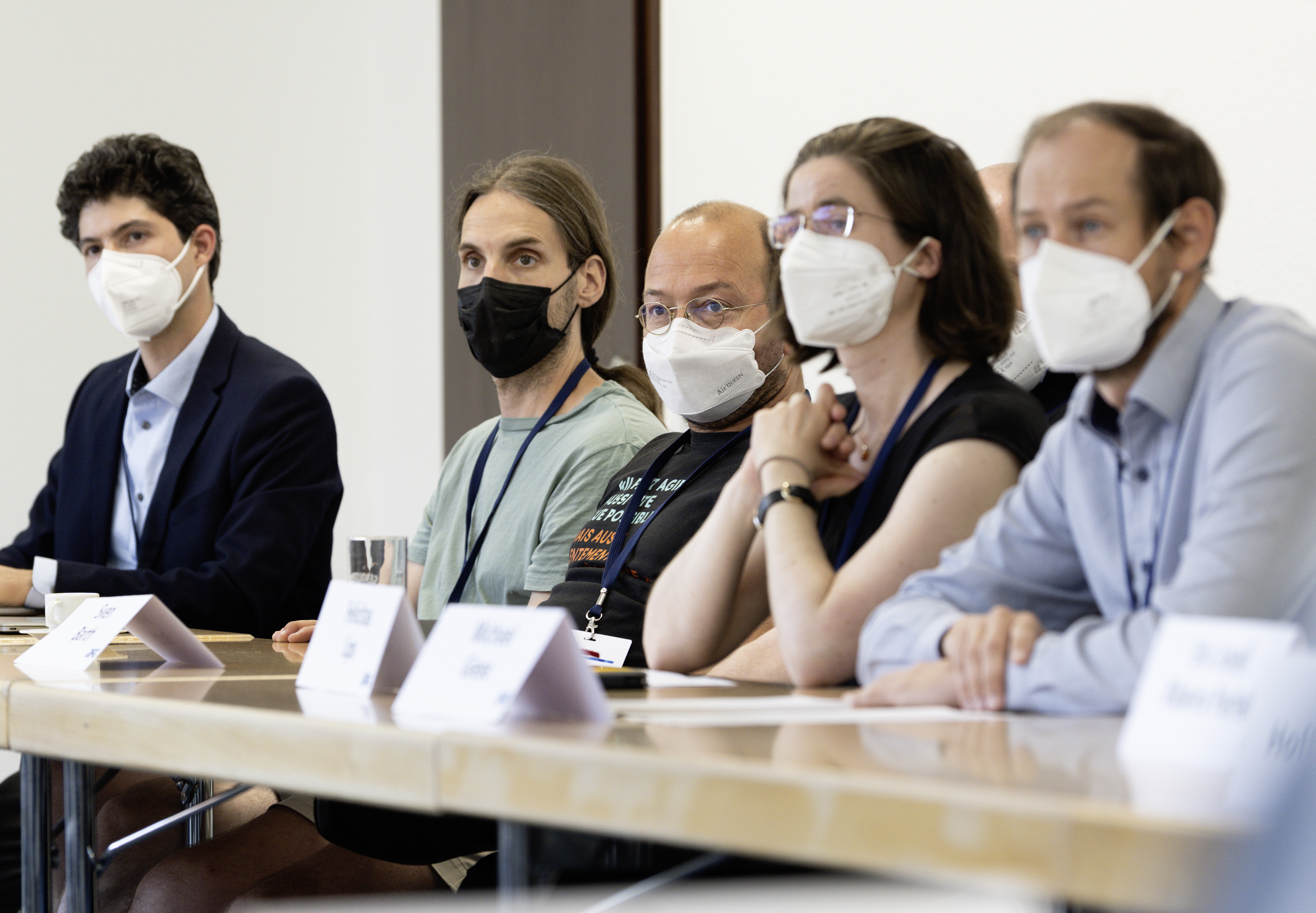 Personen sitzen in einer Reihe am Tisch für einen Workshop