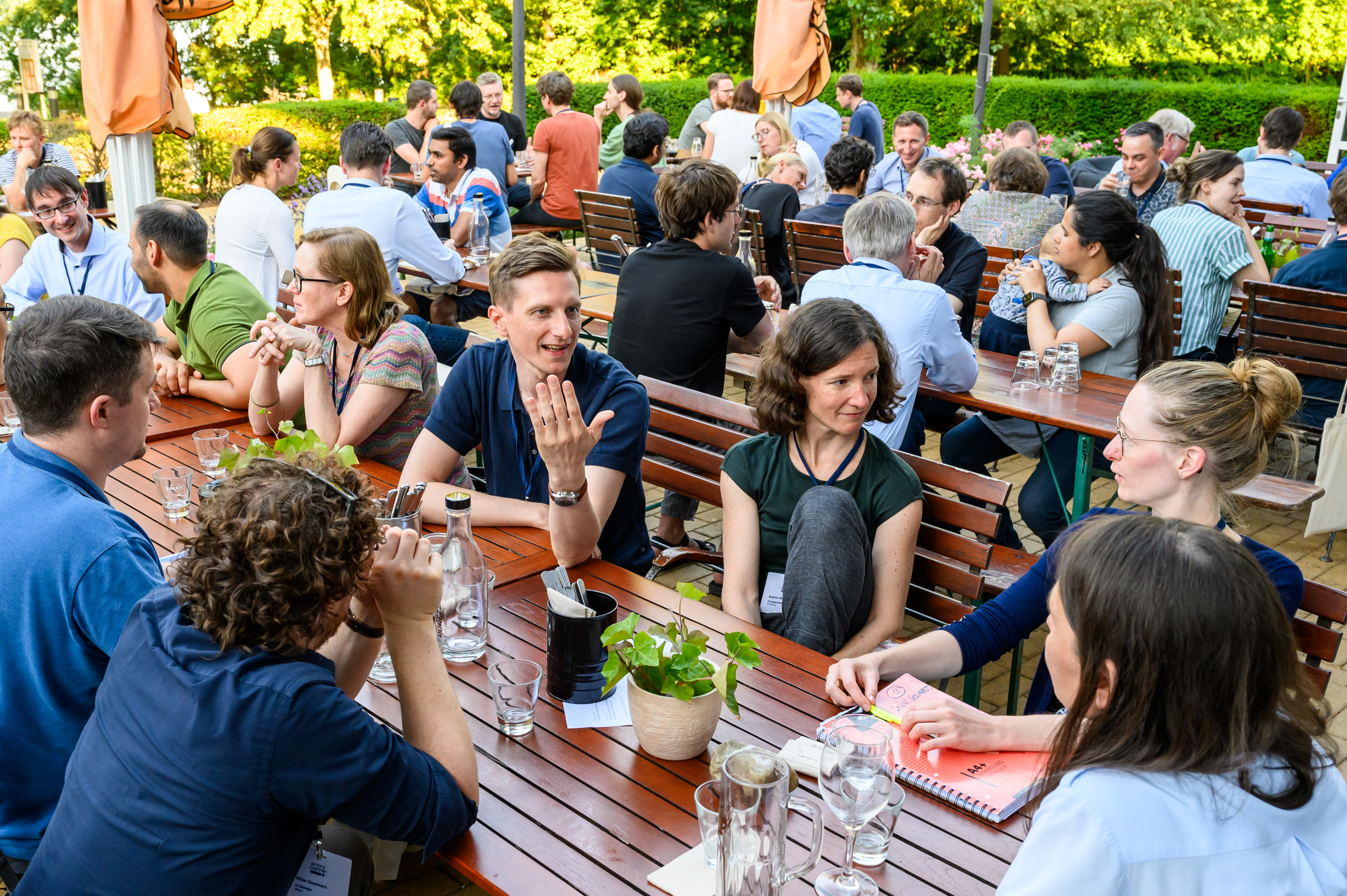 Menschen sitzen an Tischen und sprechen miteinander