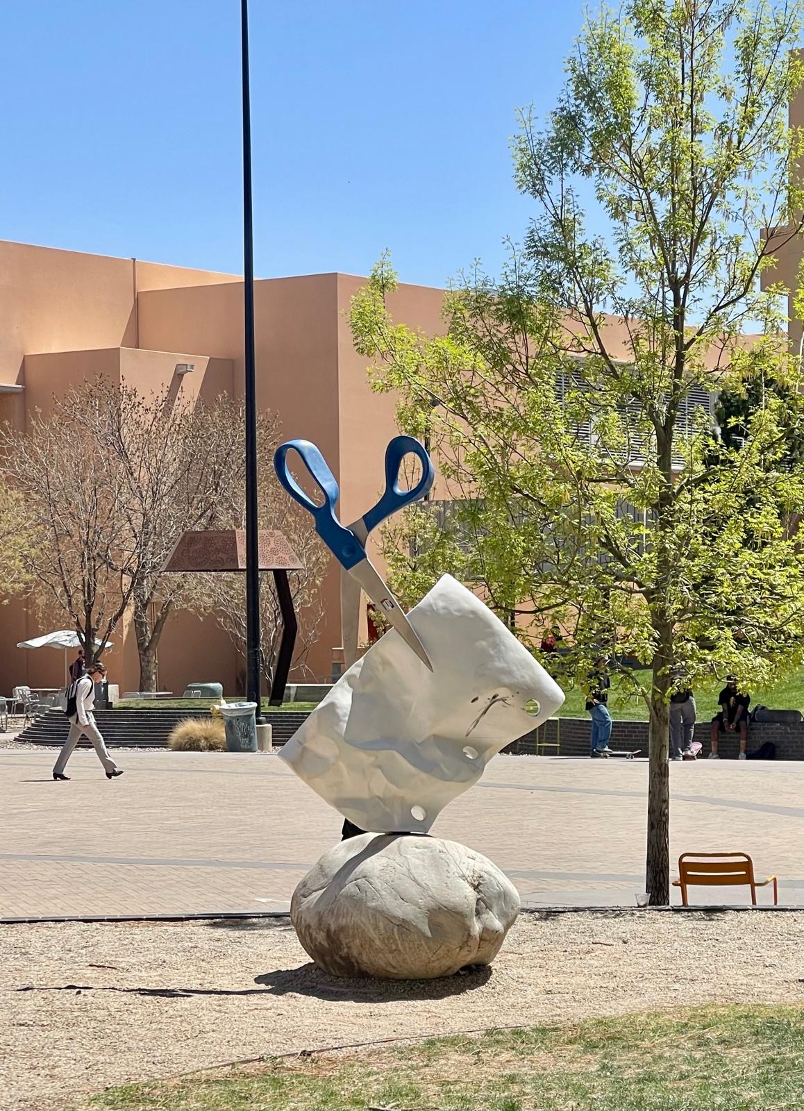 The sculpture shows a big scissor cutting a piece of paper