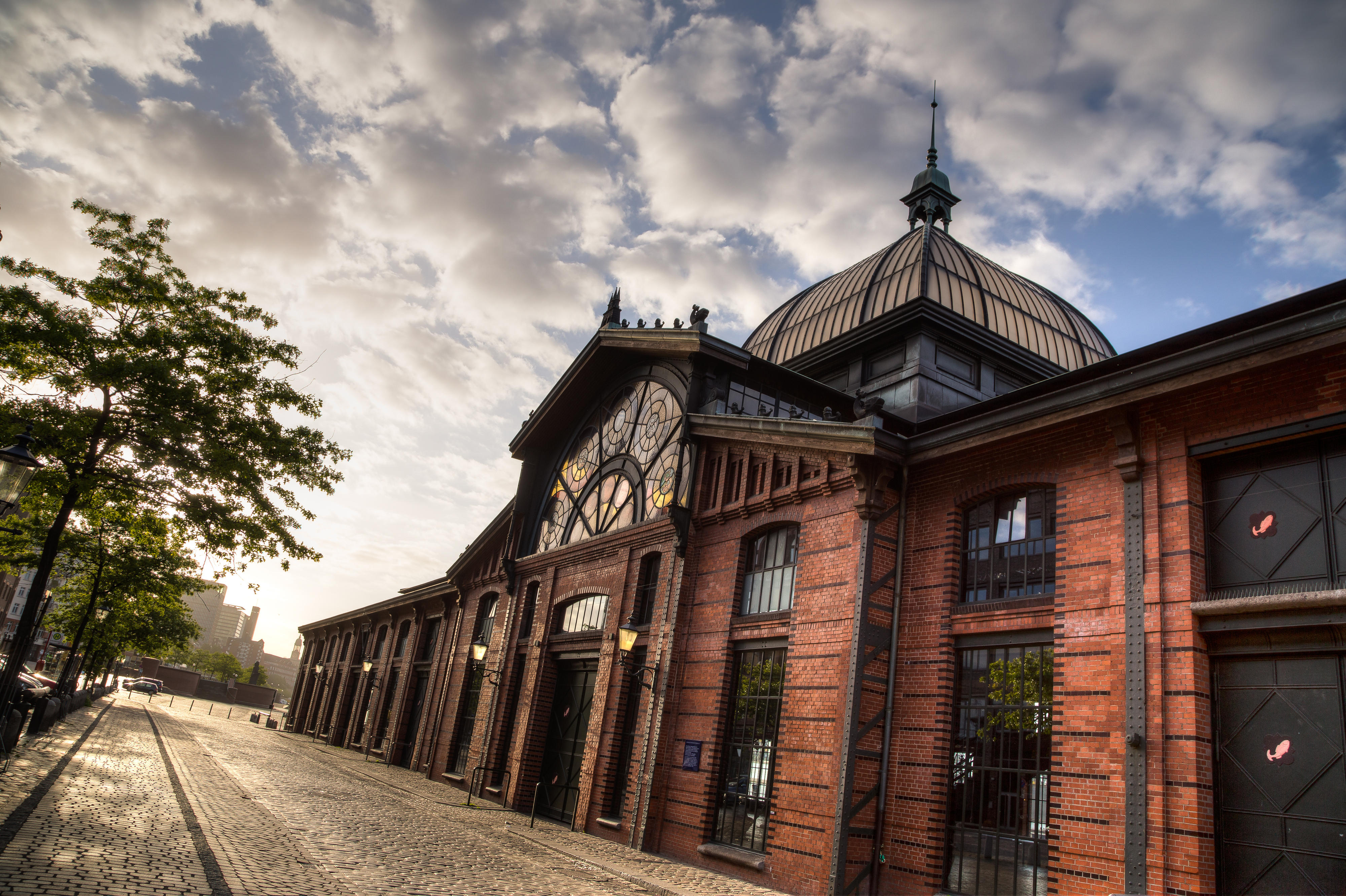 Blick von unten rechts schräg auf die Fischmarkhallen in Hamburg, ein rostrot-schwarzes Gebäude.