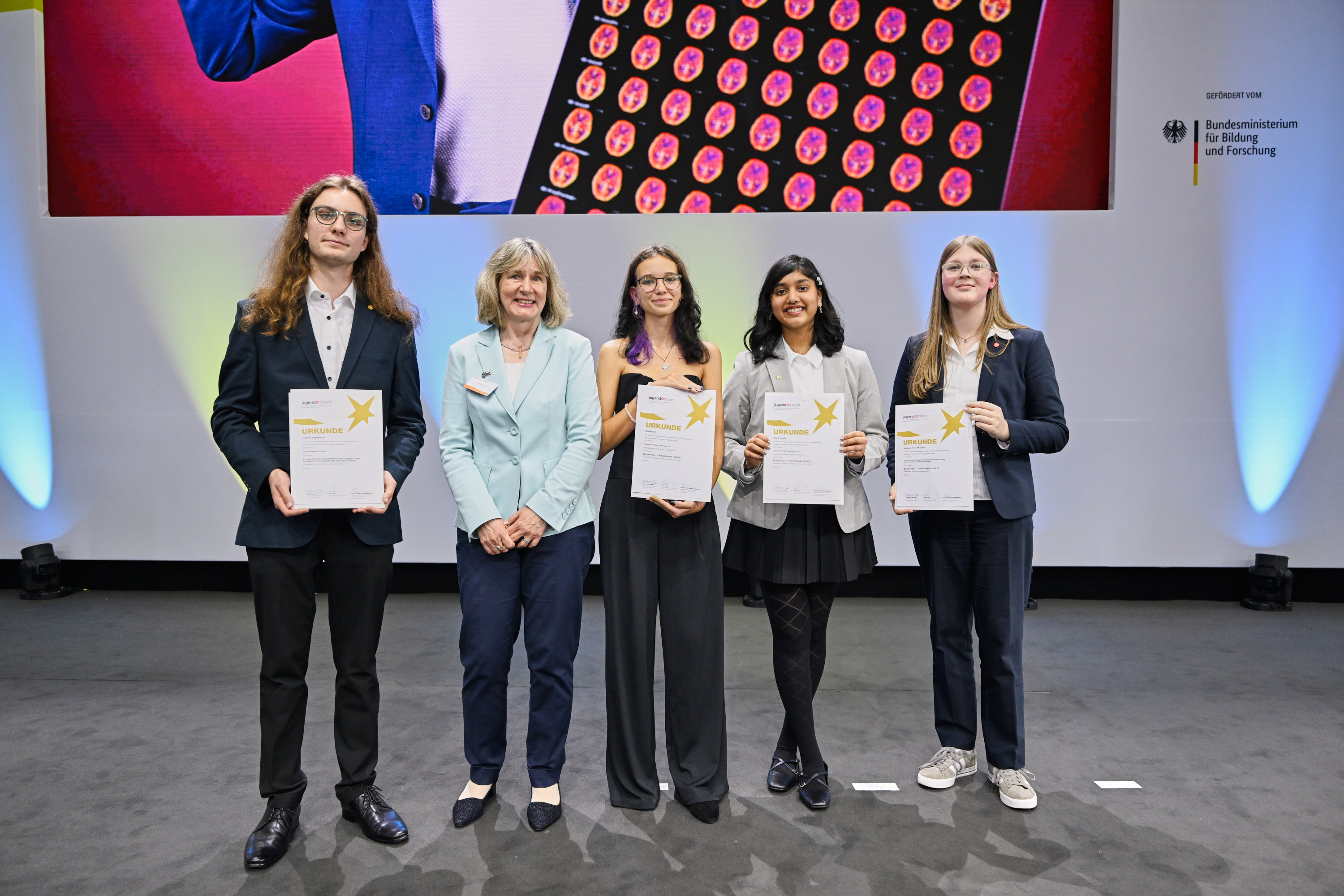 DFG-Generalsekretärin Dr. Heide Ahrens stands in the middle of the prizewinners who each hold an award certificate in front of them.