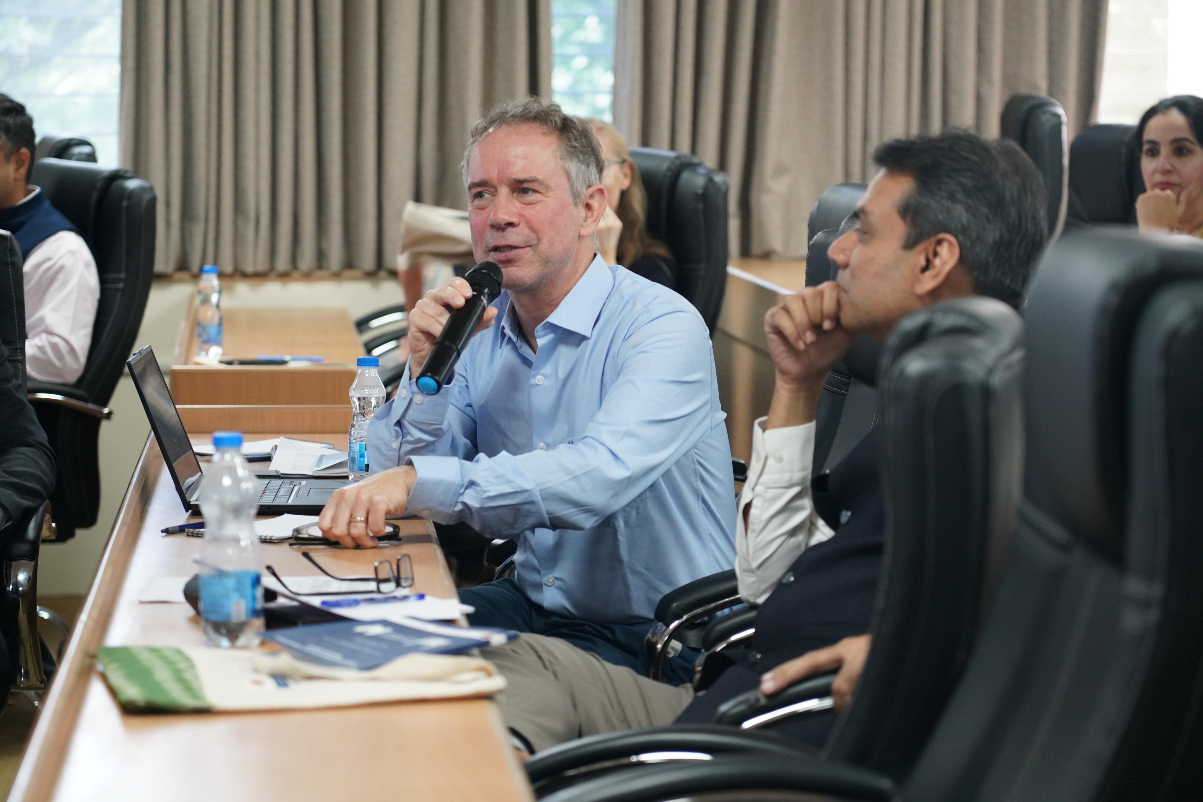 In a close-up, one participantzis speaking while a few others look at him.