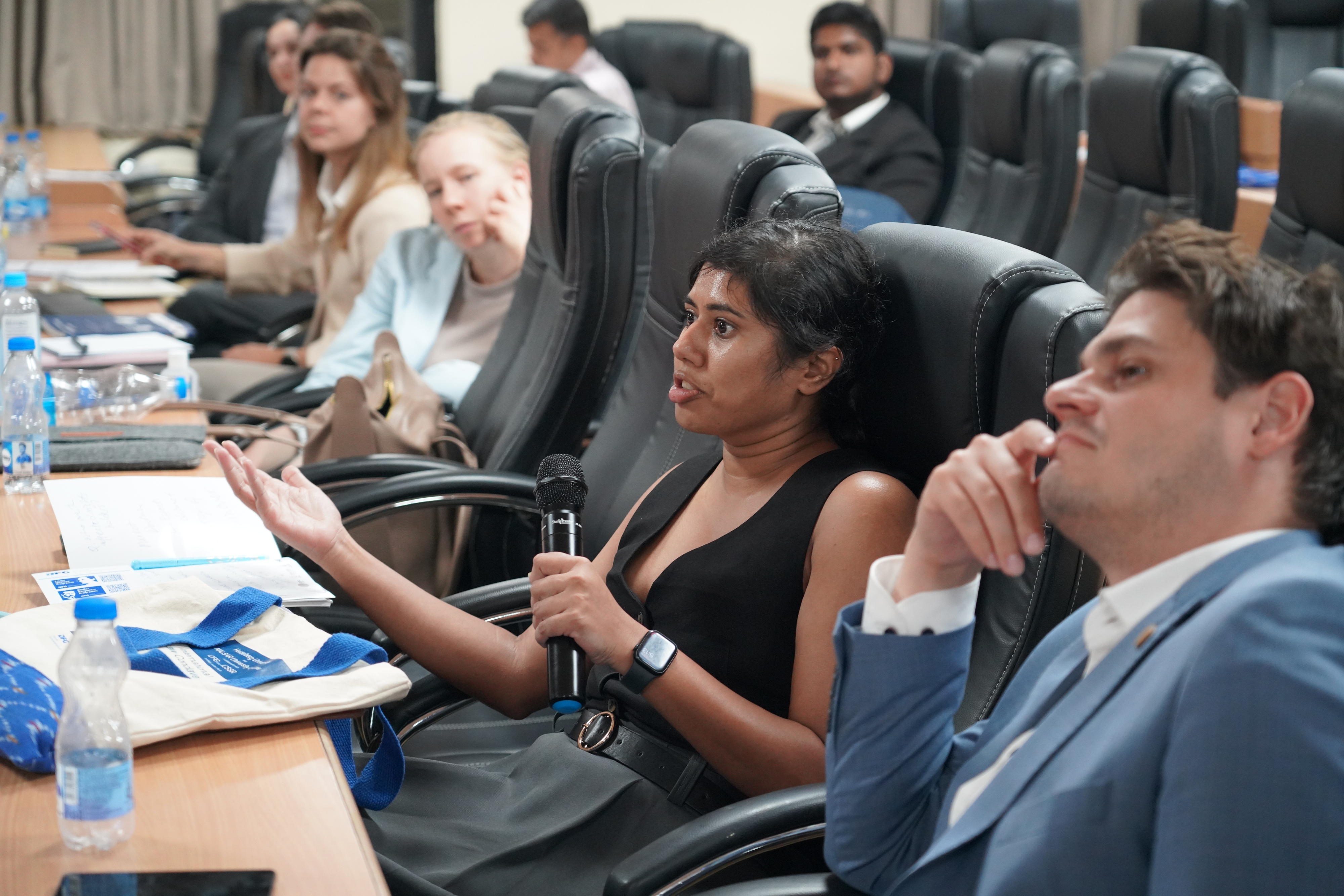 One participant is speaking while other researchers in the seats look at her or at the front.