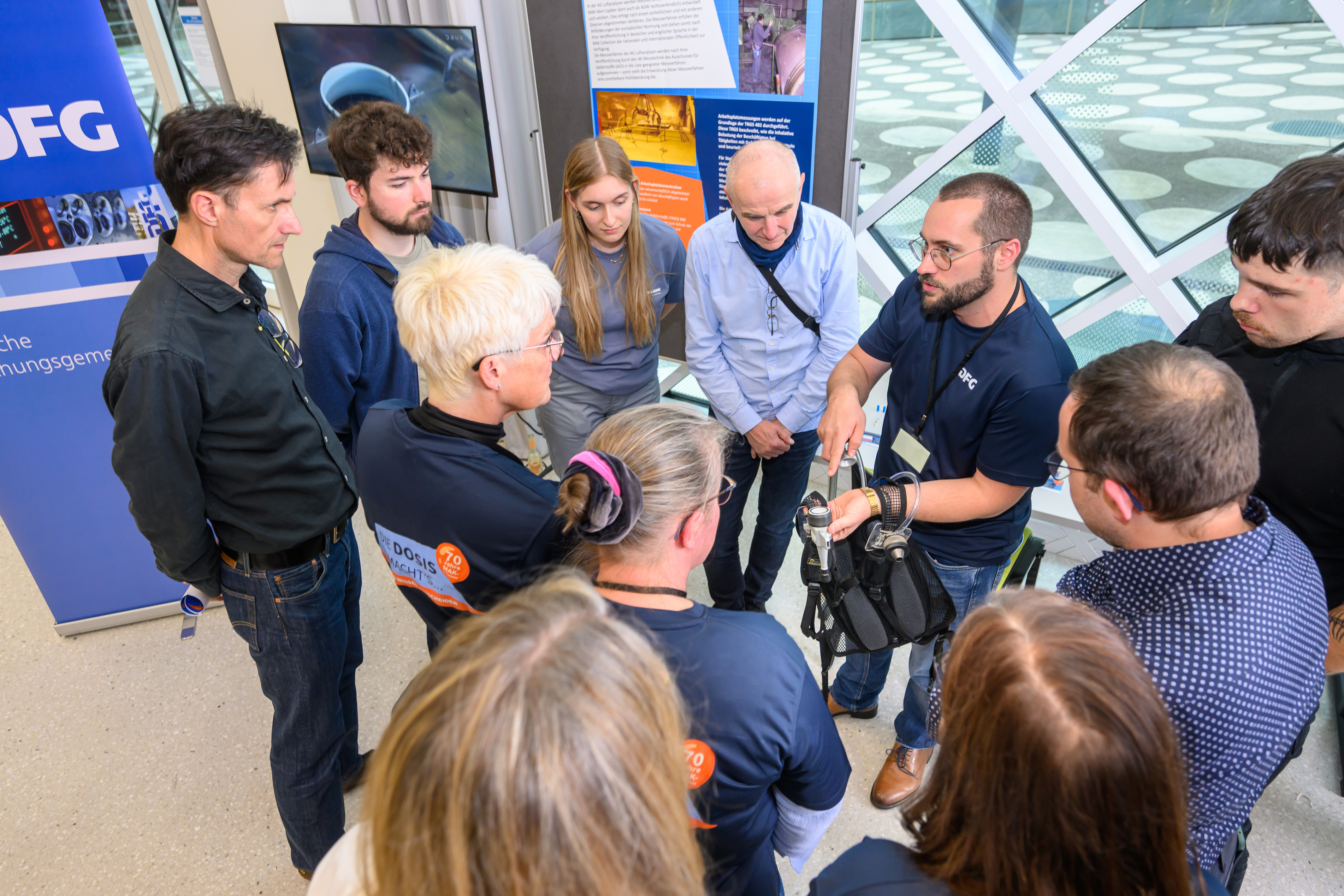 Ein Experte steht in einer Gruppe Besucher*innen und demonstriert eine Apparatur