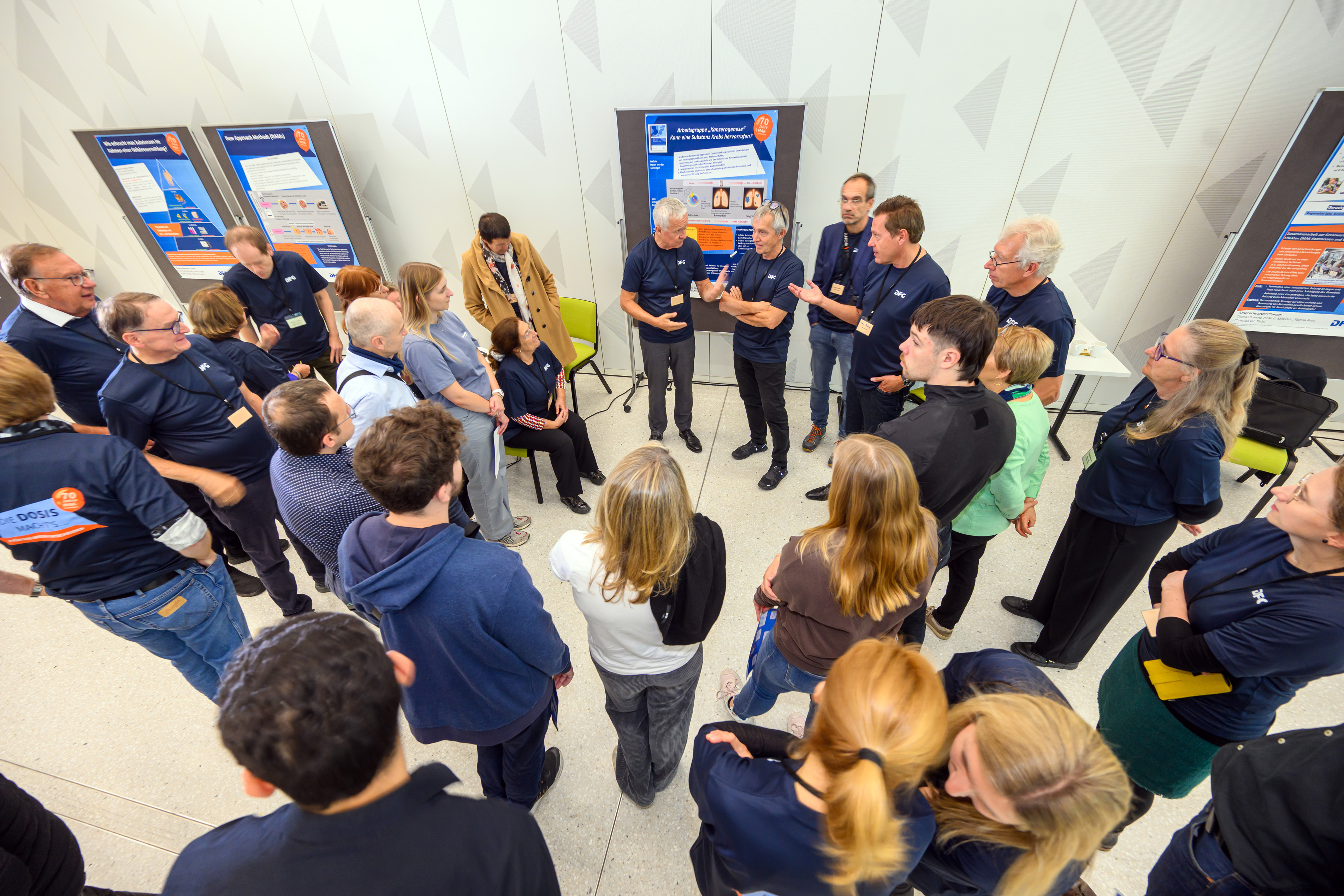 Mehrere Menschen stehen im Gespräch um ein Poster herum 