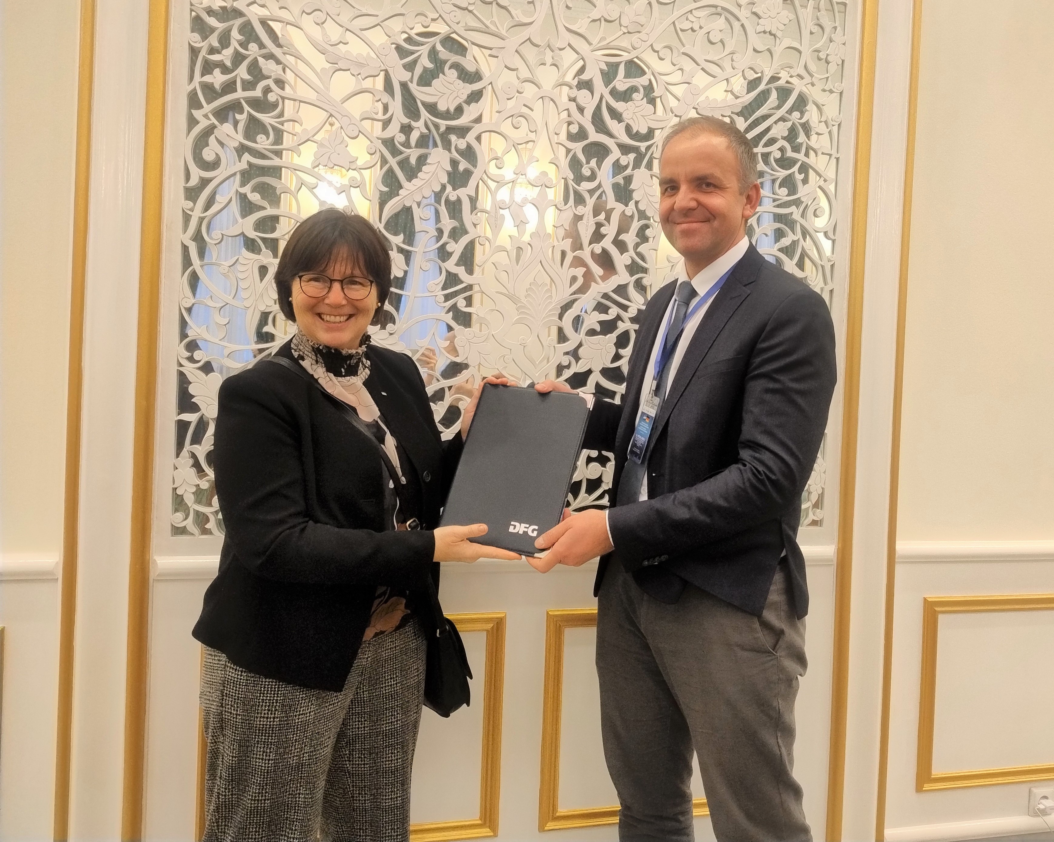 DFG Vice President Professor Dr. Karin Jacobs presents Dr. Peter Liebelt with the signed agreement at the Embassy of Uzbekistan in Berlin.