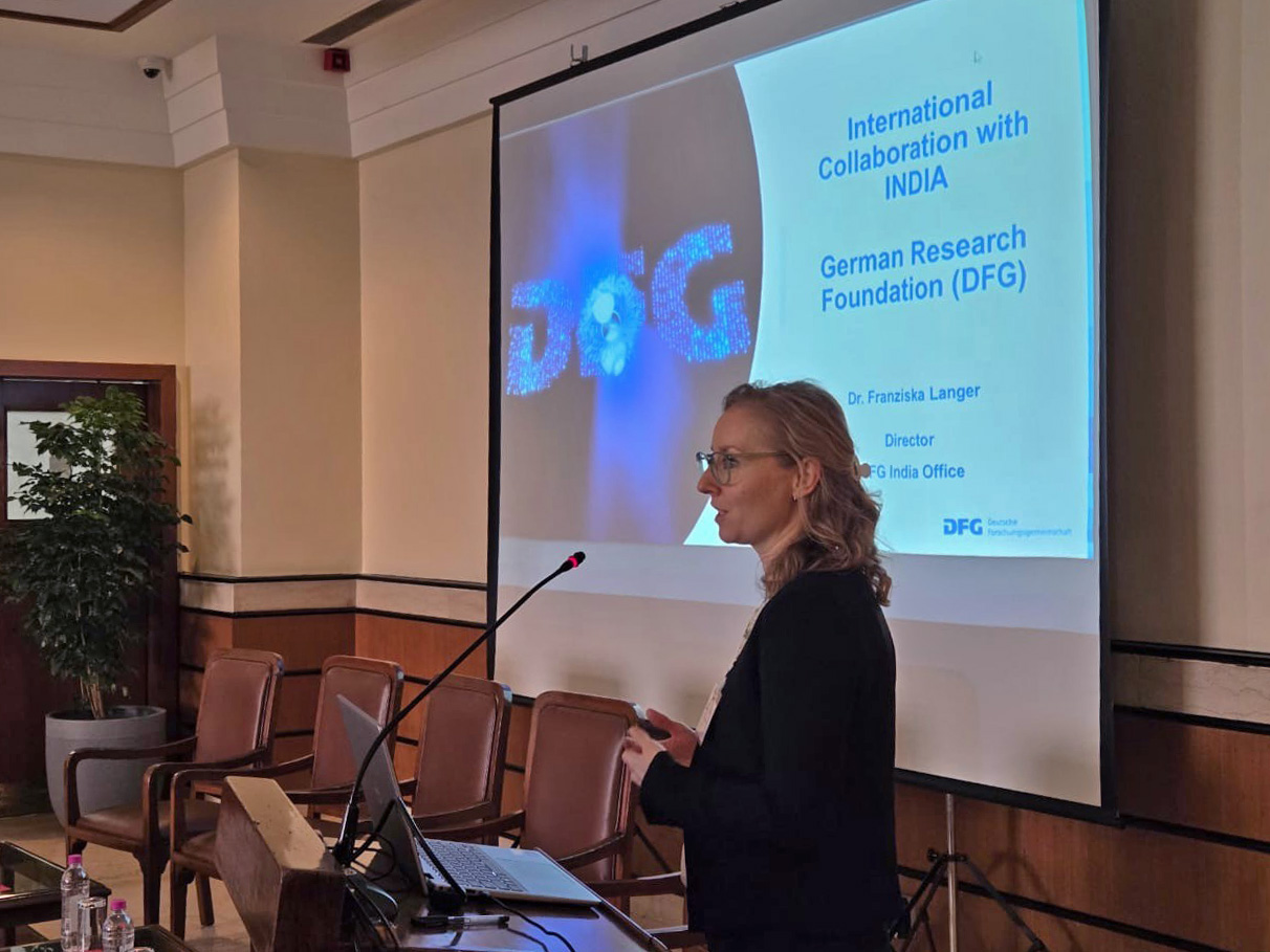 Dr. Franziska Langer standing at the speaker's desk disbursing information at the Max Planck Partner group meeting on various DFG funding programmes 