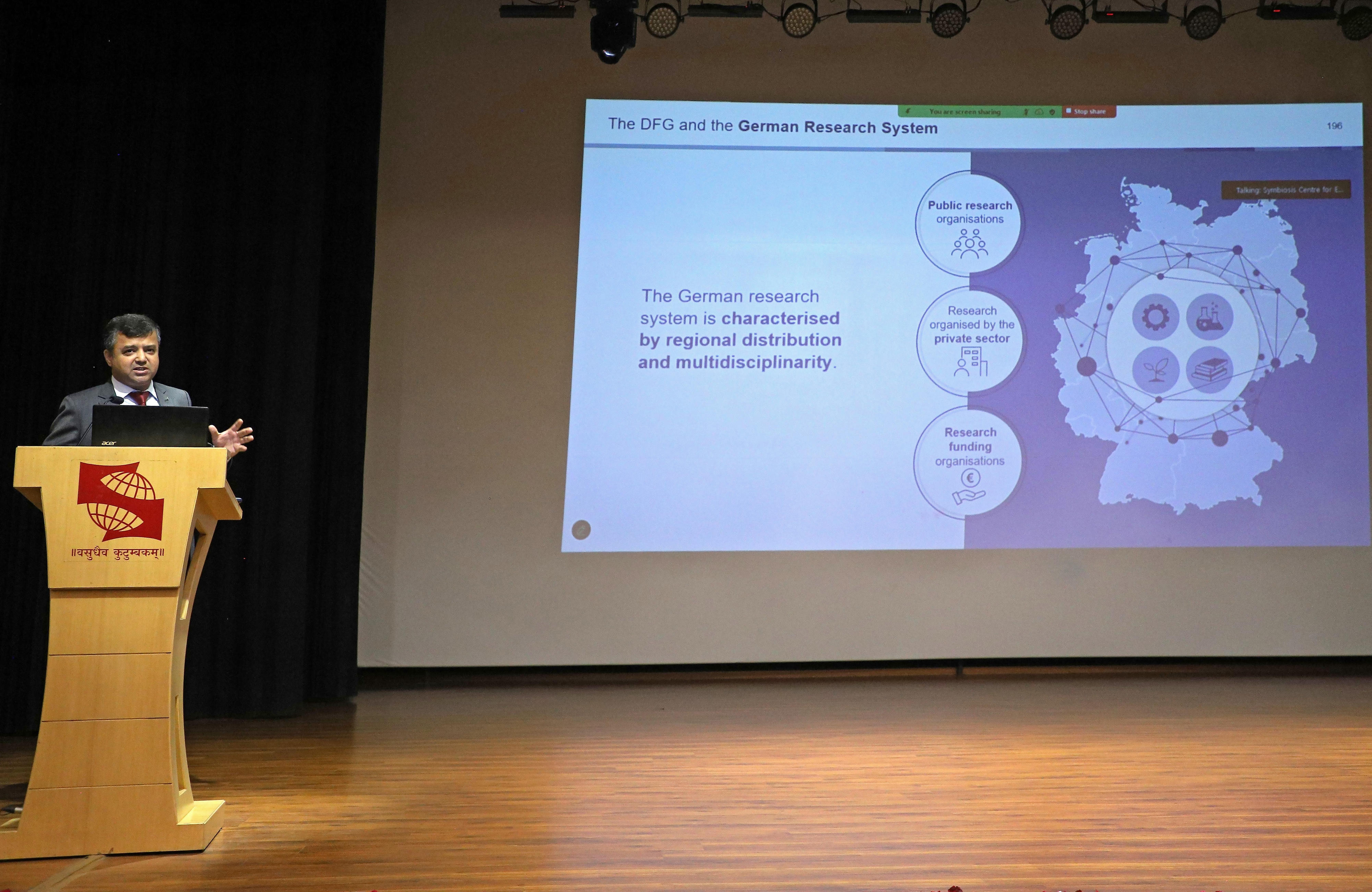 Dr. Vaibhav Agarwal, Deputy Director, DFG Office India addressing the audience at Symbiosis International University, Noida Campus at a speaker's desk.