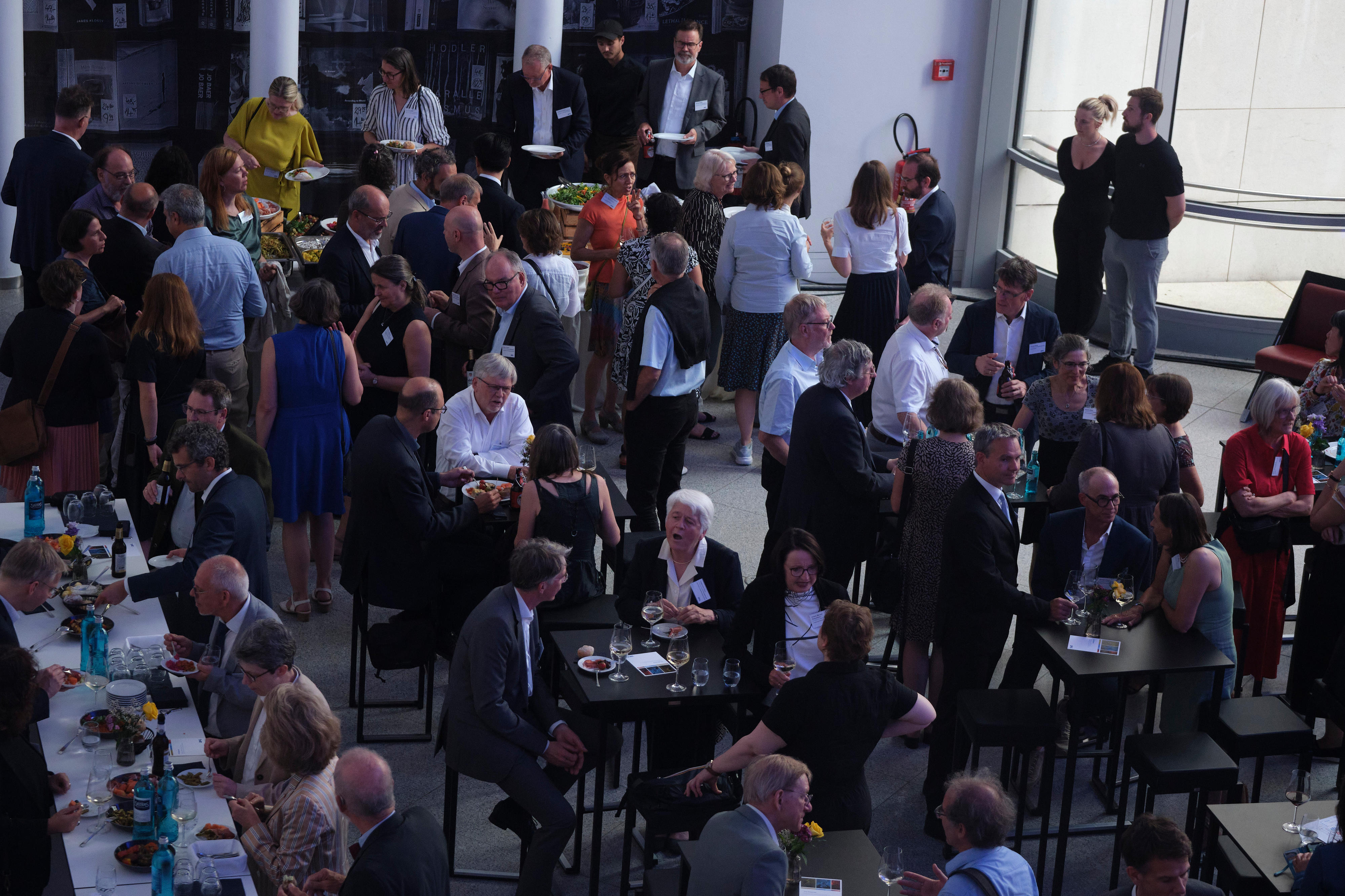 Blick ins Foyer der Bundeskunsthalle mit vielen Menschen an Tischen und im Gespräch